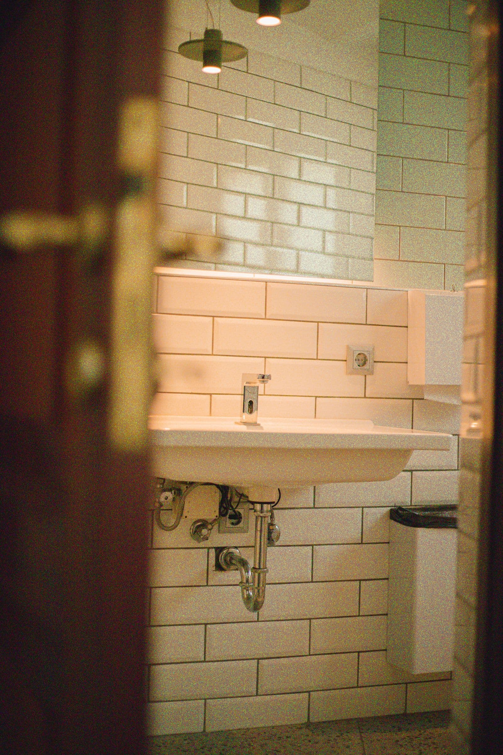 Wall-mounted bathroom sink with a chrome faucet and exposed drain plumbing