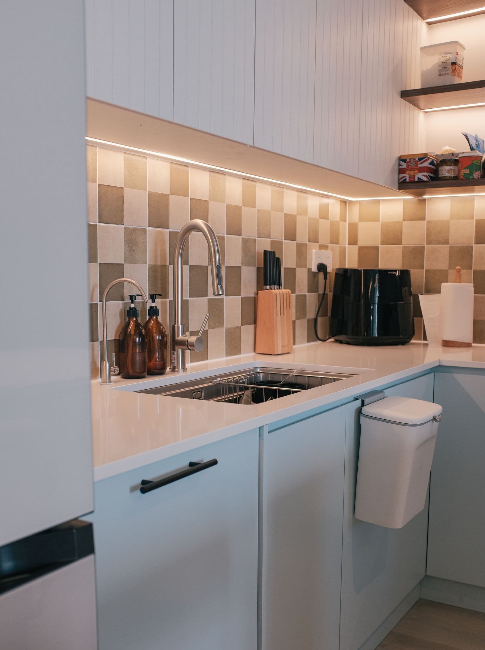 Stainless kitchen sink and faucet above a cabinet where an under-sink drinking-water system may be planned